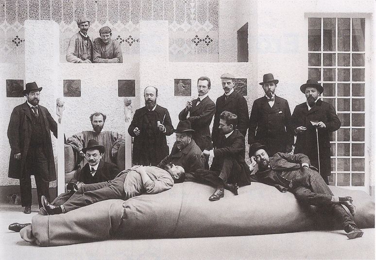 Back row from left to right: Anton Stark, Gustav Klimt (seated), Adolf Bohm, Wilhelm List, Maximilian Kurzweil )with cap), Leopold Stolba, Rudolf Bacher. FRONT ROW, LEFT TO RIGHT: Koloman Moser (seated), Maximilan Lenz, Ernst Stohr, Emil Orlik, Carl Moll