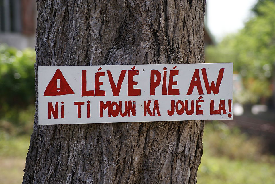 Creole Roadsign "Lift [your] foot (i.e., slow down), children are playing here!"